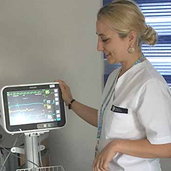 uma mulher de bata branca a olhar para um monitor