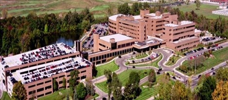 um edif&iacute;cio com estacionamento e um lago